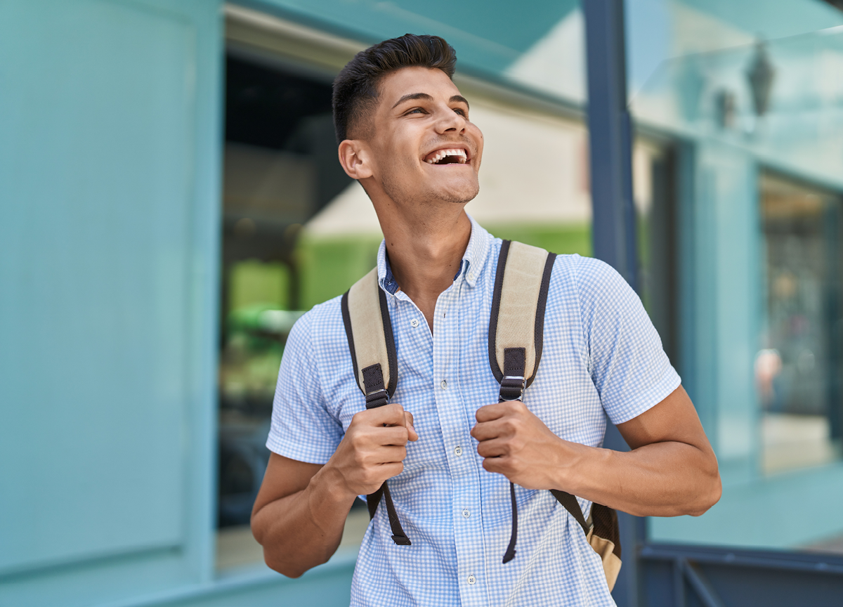 Young hispanic man student smiling confident standing at street