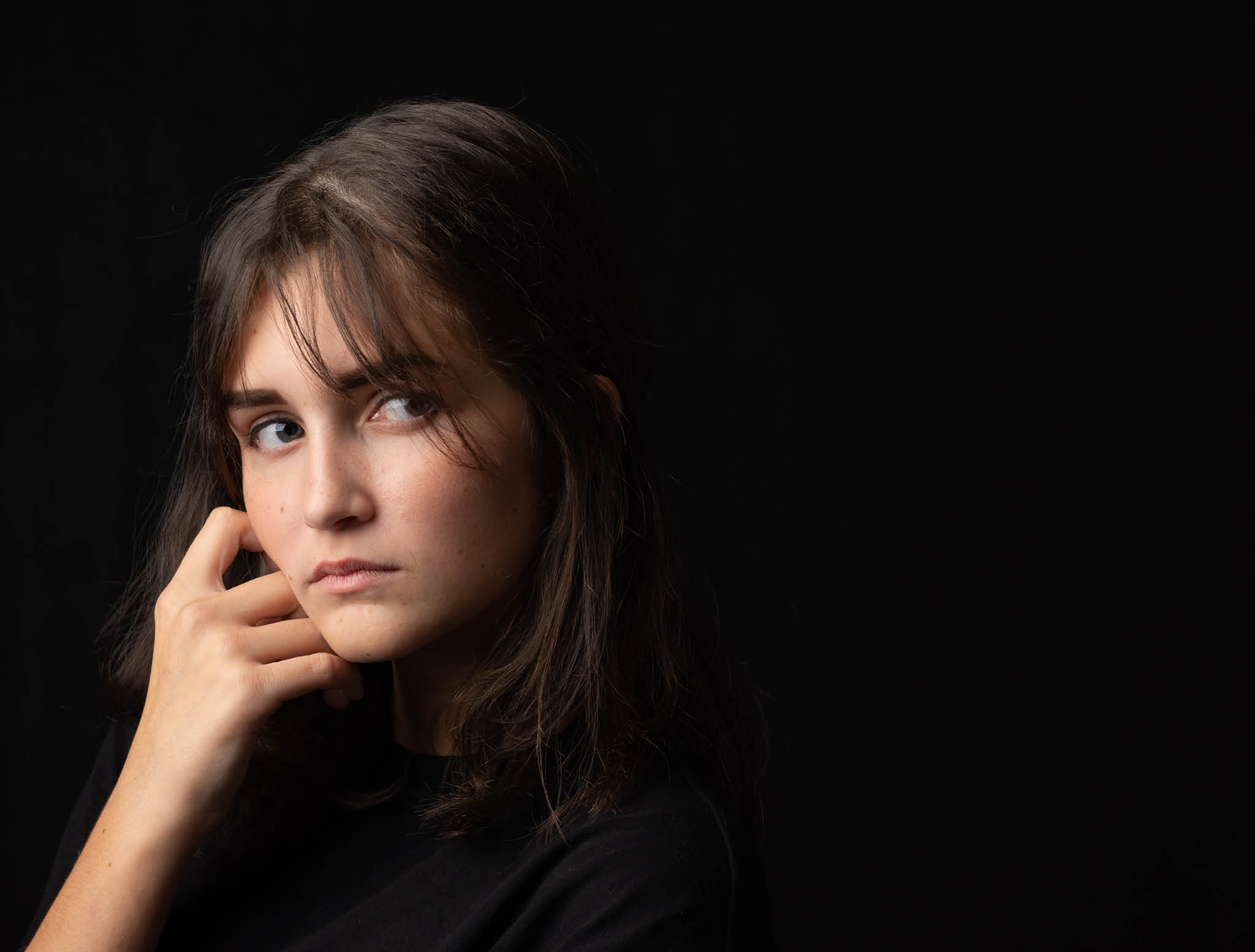 Art portrait of sixteen year old teenage girl in dark clothes on black background