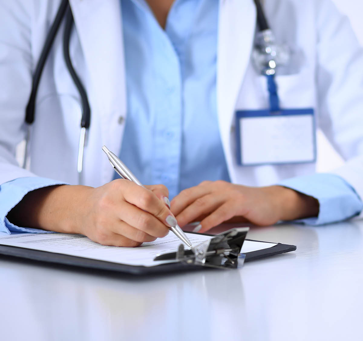 Doctor woman filling up medical form while sitting at the desk in hospital office. Physician at work. Medicine and health care concept.