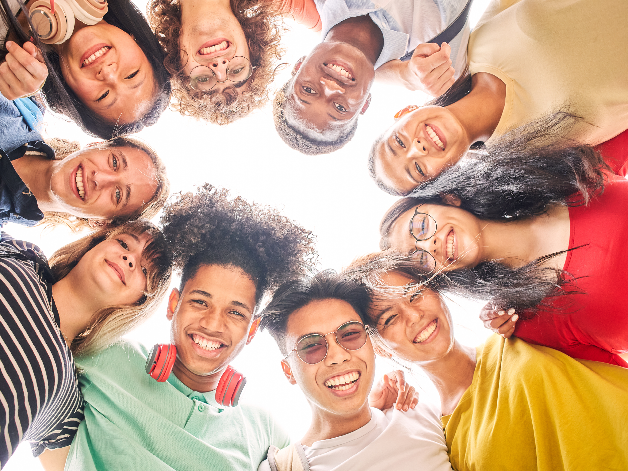 Low angle of a group of students are together, happy and smiling. Faces of young teenagers looking at camera, hugging.