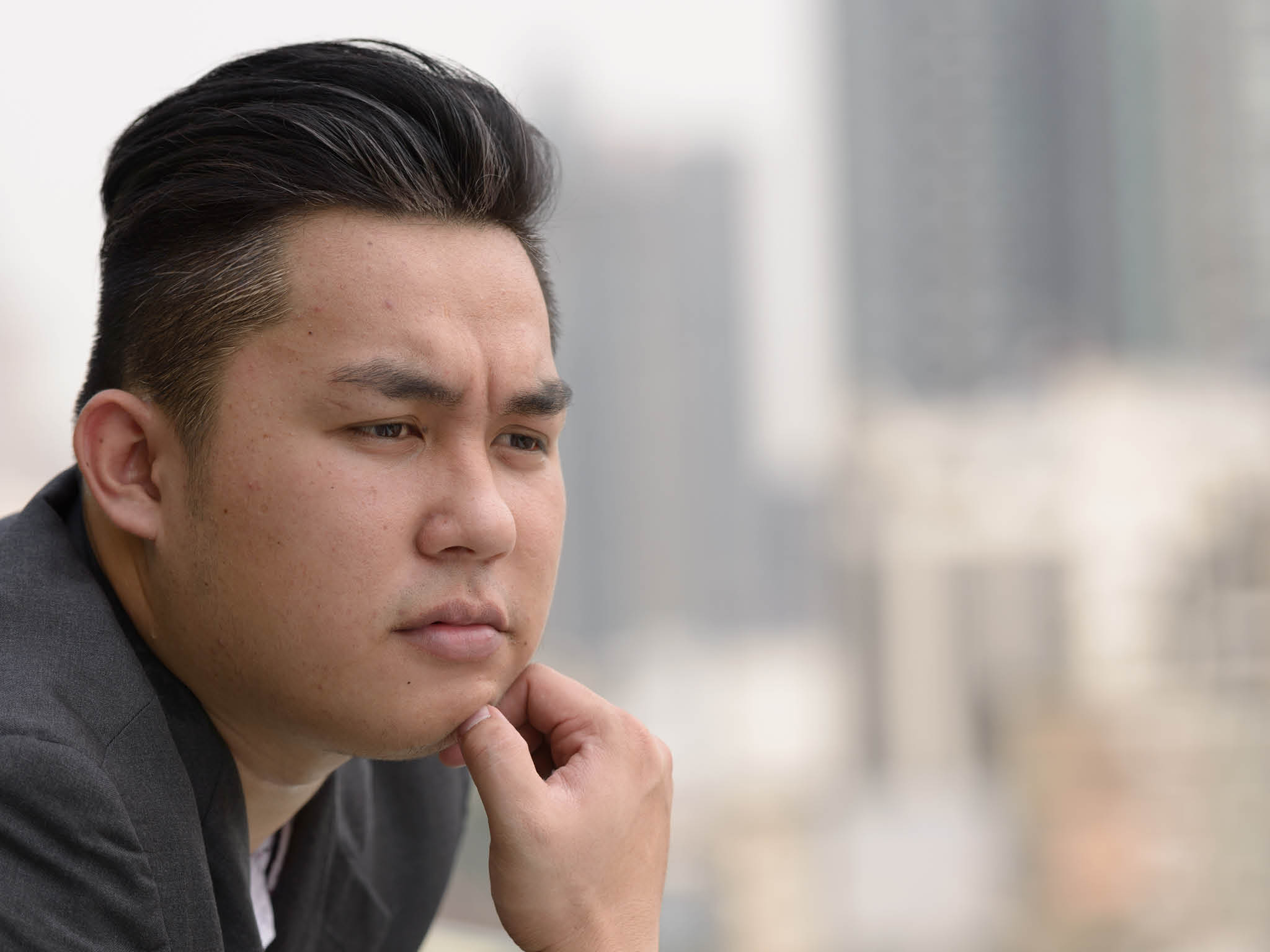 Portrait of young handsome overweight Filipino businessman in suit against view of the city