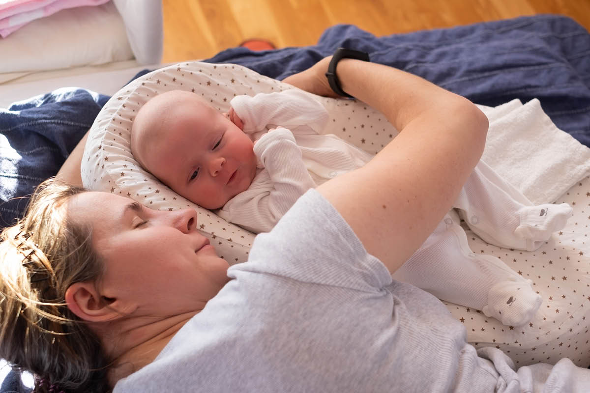 close up portrait of mother with a baby resting on bed. Top view