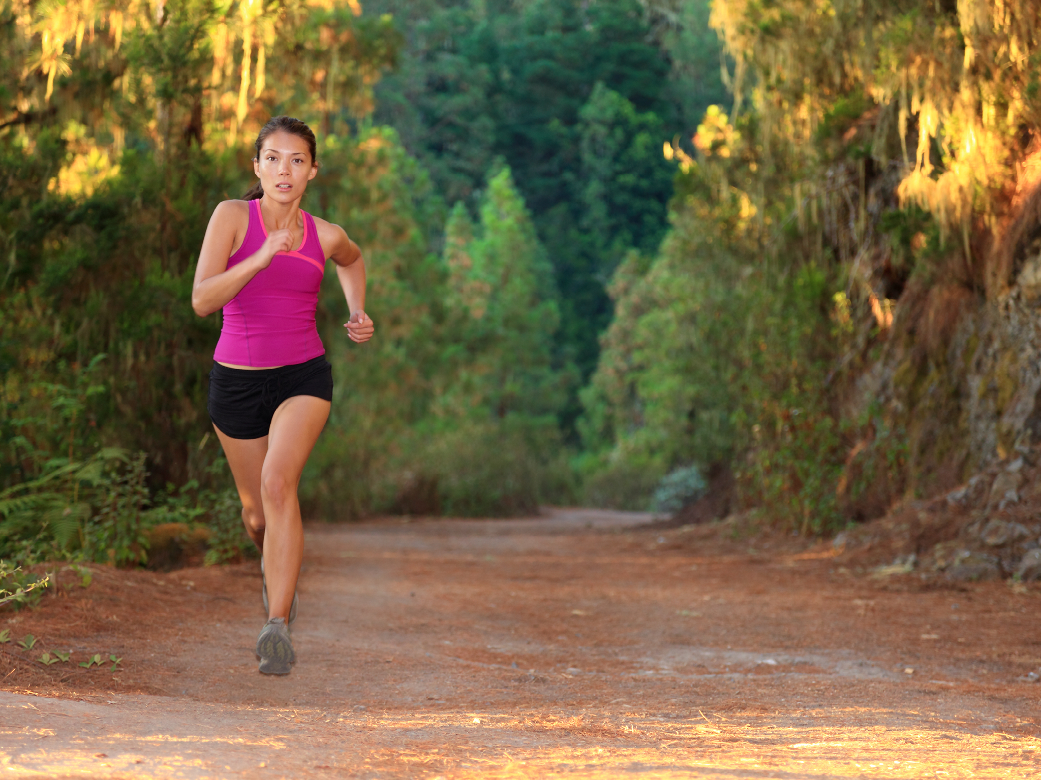 Female athlete running on forest road - copy space. Chinese Asian / Caucasian female woman runner.