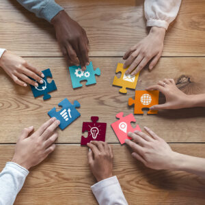 Coworkers sitting around table, teamwork, each brings different resources.