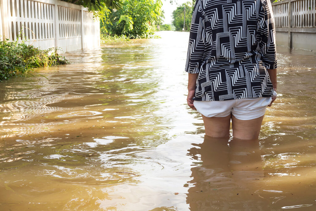 Woman wade flooding in her house. Closeup on her leg.