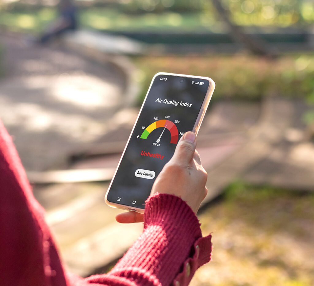 A woman checking the outdoor air quality index using an app on her smartphone.