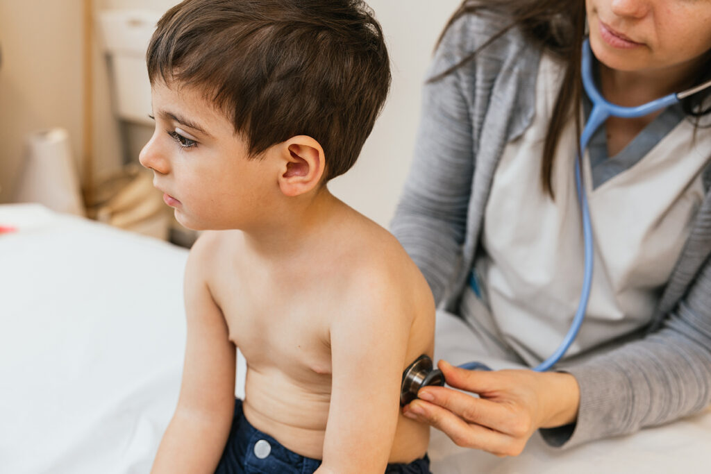 Pediatrician examining a child's lungs using a stethoscope during a medical consultation.