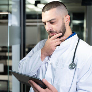 Concerned ER doctor looking at tablet computer. 